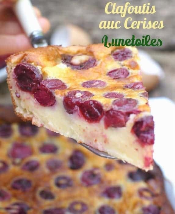 Close-up of a slice of traditional French cherry clafoutis with golden custard and baked whole cherries, being lifted from the dish