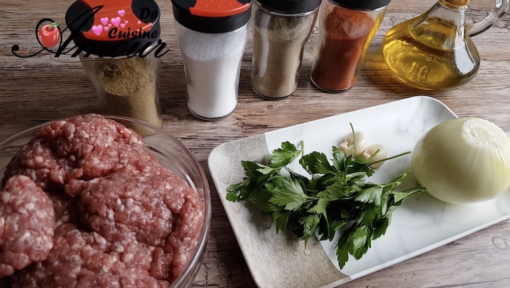 Ingredients for kefta skewers including ground meat, parsley, onion, garlic, olive oil, and spices like cumin, salt, pepper, and paprika displayed on a wooden surface