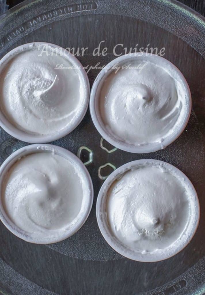 Four individual ramekins filled with freshly whipped meringue, ready to be cooked in the microwave. The meringue has a smooth, glossy texture with soft peaks, and the ramekins are arranged on a microwave turntable