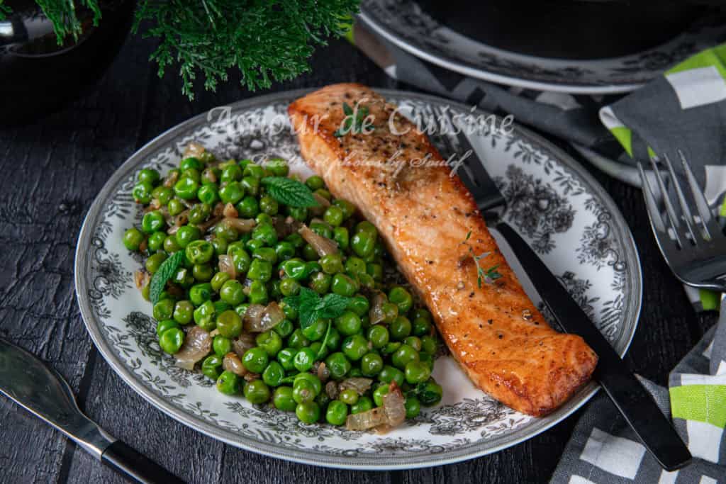 A beautifully plated meal featuring a golden-brown air-fried salmon fillet served alongside sautéed green peas with caramelized onions and fresh mint, presented on a vintage-style floral plate with a knife and fork on the side