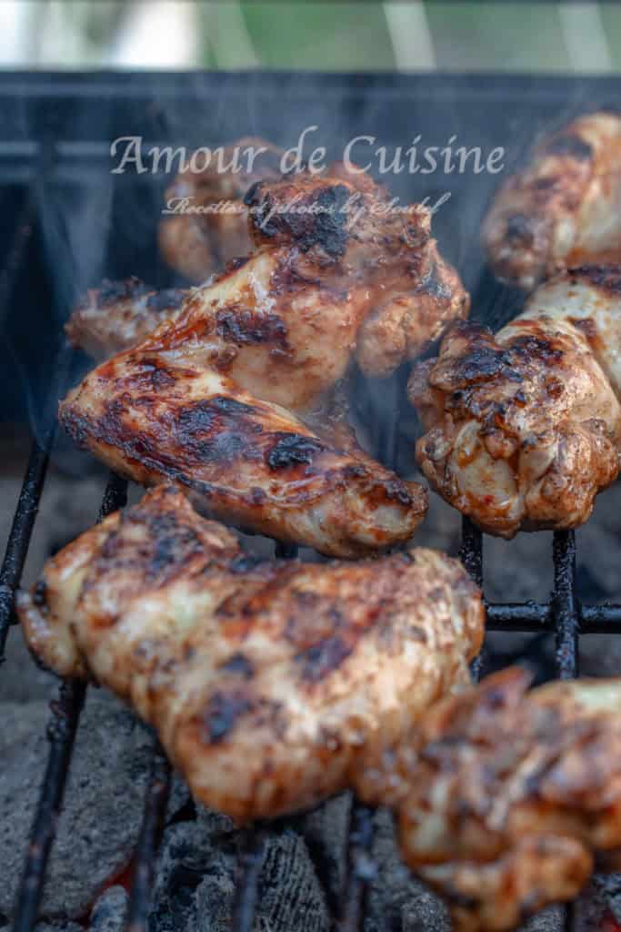 Juicy barbecue chicken wings sizzling on a charcoal grill, with visible grill marks and smoke rising, capturing the rich, smoky aroma and golden-brown crispiness of the meat in the middle of cooking