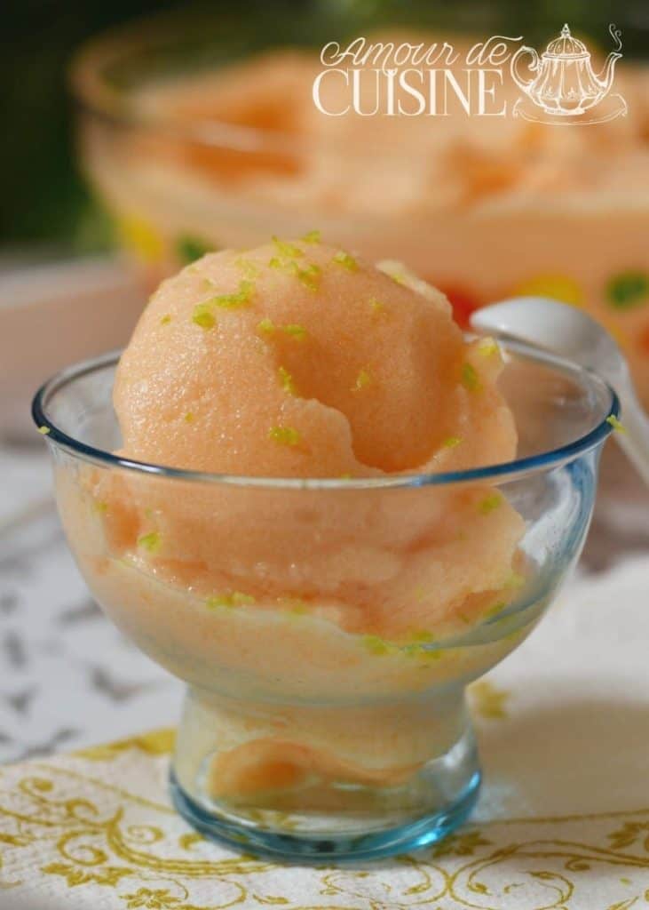 Homemade melon sorbet served in a clear glass dish, garnished with fresh lime zest, with a soft and creamy texture perfect for summer